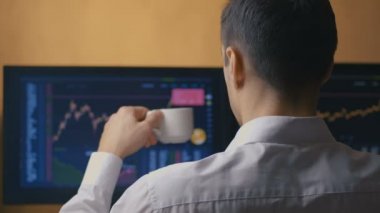 İşadamı bilgisayarda çalışıyor, kahve içiyor, dikiz aynasından bakıyor. Erkek müdür piyasadaki hisse senedi satış istatistiklerine bakıyor..