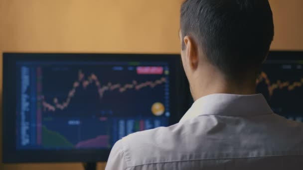 Homem de negócios está estudando gráficos de vendas em um monitor de computador. O corretor está assistindo estatísticas de vendas de ações. Conceito de investimento — Vídeo de Stock