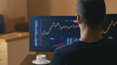 Erkek işadamı bilgisayar monitöründe satış grafikleri okuyor ve kahve içiyor. Komisyoncu hisse senedi satış istatistiklerini izliyor. Yatırım kavramı