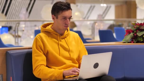 Ung man som arbetar på laptop i ett stort modernt café — Stockvideo