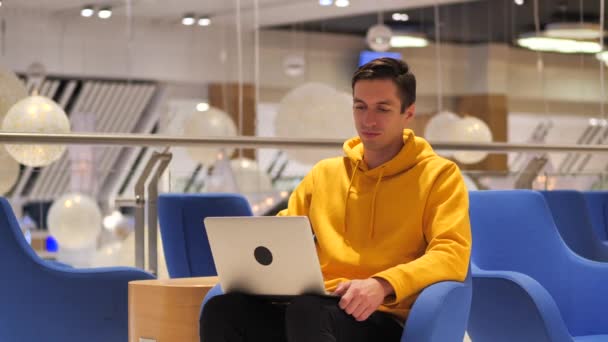 Молодий впевнений зайнятий чоловік працює на ноутбуці, сидячи в кафе — стокове відео