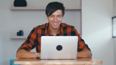 Portrait of Handsome Smiling Man Freelancer Working on Laptop, Sitting at Desk at Home.