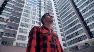 Portrait of Young professional man looking around on urban background of skyscraper building.