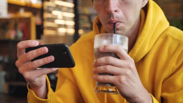 Primer plano del hombre utilizando la pantalla táctil del teléfono inteligente en la cafetería moderna. y Beber batido o batido — Vídeos de Stock