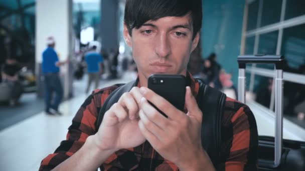 Reação agressiva do homem louco do mal à mensagem ou notícias em um smartphone enquanto espera no aeroporto — Vídeo de Stock