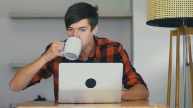 Kendine güvenen işadamı dizüstü bilgisayarda çalışıyor ve evde kahve içiyor..