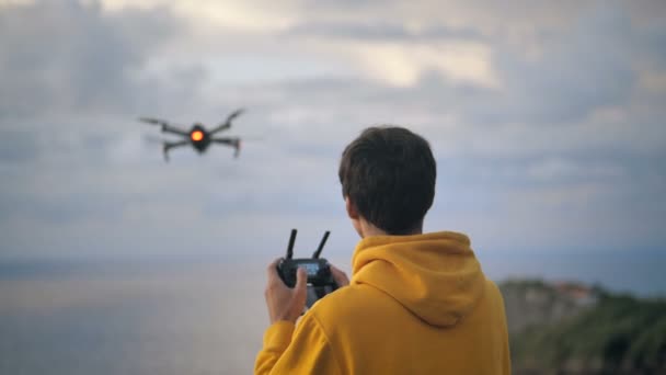 Человек путешественник делает фотографии или видео с помощью дрона. Мужчина учится летать и снимать видео на квадрокоптере дрона во время путешествия. Современная концепция хобби — стоковое видео