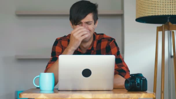 Droevige man fotograaf huilt tijdens zijn werk thuis op laptop. Creatief crisisconcept. — Stockvideo