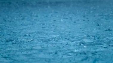 Close-up rainfall, raindrops falling to the surface of the water. Storm. Rain season.