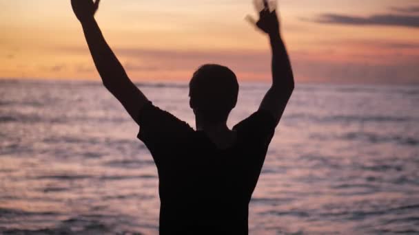 Silhouette of man raises his hands up standing back on beautiful tropical beach on red sunset. Freedom concept. — Stock Video