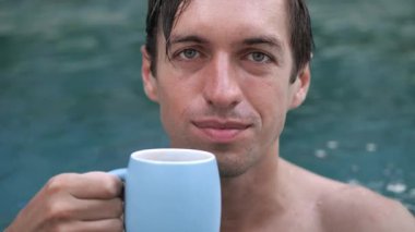 Yüzme havuzunda kahve içen genç bir adamın yakın çekimi.