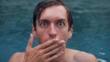 Korkutucu bir şey gören, şok olmuş gibi görünen, elleriyle nefes nefese kalan, ürkek bakışlı, yüzme havuzunda başını sallayan bir adam..