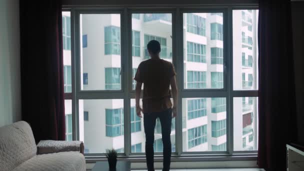 Silhouette de jeune homme regardant la fenêtre de la pièce. Le concept de rêve et de succès . — Video