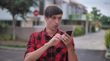 Şaşkın adam kazananın elinde akıllı telefon var. İyi haberler okunuyor. Mobil online bahis bahsi kazanınca hayrete düşüyor. Mutlu erkek cep telefonu ekranına bakıyor..