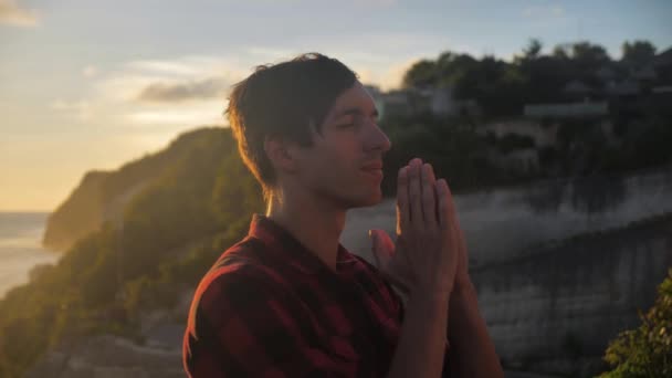 Porträtt av en man som ber till Gud på toppen av berget ovanför vackert landskap på gyllene solnedgång. Begreppet religion — Stockvideo