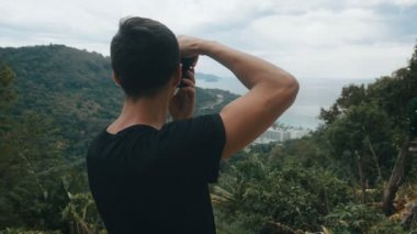 Gezgin, dağda resim çekerek fotoğraf çekiyor. Erkek turist dışarıda fotoğraf çekiyor. Profesyonel fotoğrafçı..