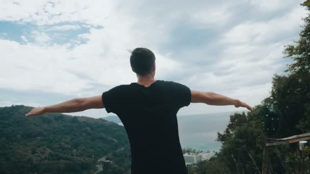 Jonge man reiziger steekt zijn handen hoog op de top van de berg boven prachtig landschap — Stockvideo