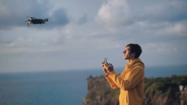 One man tourist controlling innovation aviation unmanned aircraft drone. Young traveler using panel connected to mobile smart phone. Concept of quadcopter shooting
