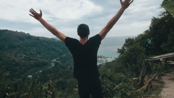 Jeune homme voyageur levant les mains haut sur le sommet de la montagne au-dessus du beau paysage — Video