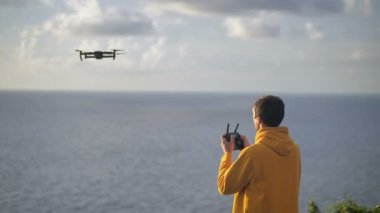 Erkek gezgin insansız hava aracı kullanarak fotoğraf ya da video çeker. Erkek, uçmayı ve seyahet ederken bir dron kuadkopterinde video çekmeyi öğreniyor. Modern hobi konsepti