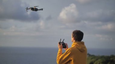 Erkek gezgin insansız hava aracı kullanarak fotoğraf ya da video çeker. Erkek, uçmayı ve seyahet ederken bir dron kuadkopterinde video çekmeyi öğreniyor. Modern hobi konsepti