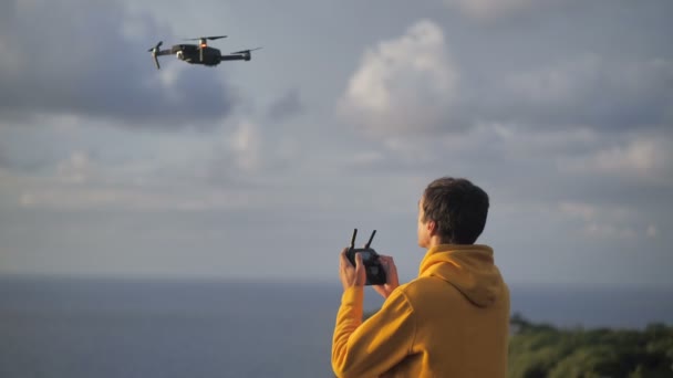 Человек путешественник делает фотографии или видео с помощью дрона. Мужчина учится летать и снимать видео на квадрокоптере дрона во время путешествия. Современная концепция хобби — стоковое видео