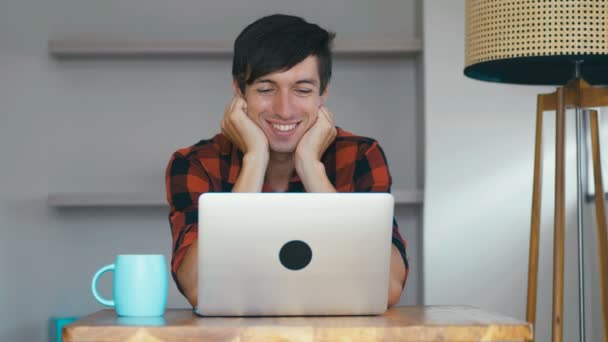 用笔记本电脑描绘笑容满面的快乐男人。自由职业者喜欢在家里的电脑上工作和喝咖啡. — 图库视频影像