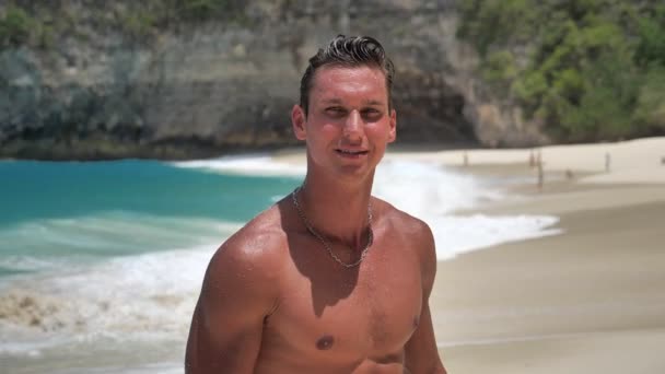 Yakışıklı genç adamın portresi, iyi eğitimli kaslı atlet, güzel kumsalda poz veriyor. — Stok video