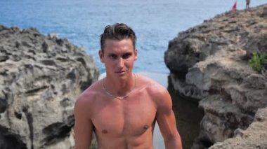 Yaz öğleden sonra sahilde deniz kenarında poz veren yakışıklı kaslı adam modeli.