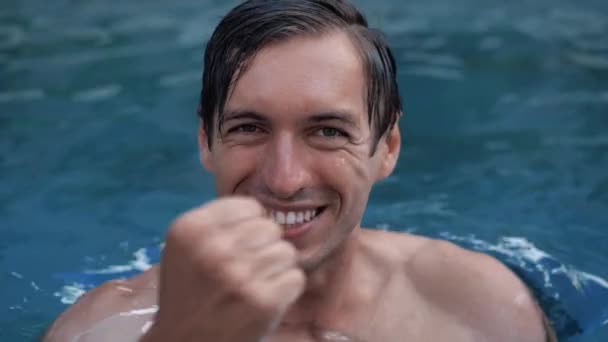 Lenyűgözött fiatalember megdöbbent mutatja igen győztes gesztus a nyaralás a medencében. A sportoló úszó örül a győzelemnek. — Stock videók