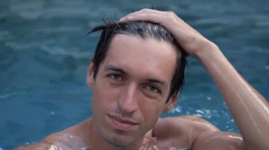 Mutlu gülümseyen bir adamın yakından çekilmiş portresi havuzda keyif çatıyor.