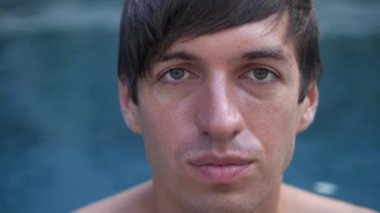 Genç bir adamın yakın plan portresi havuzda keyif çatıyor.