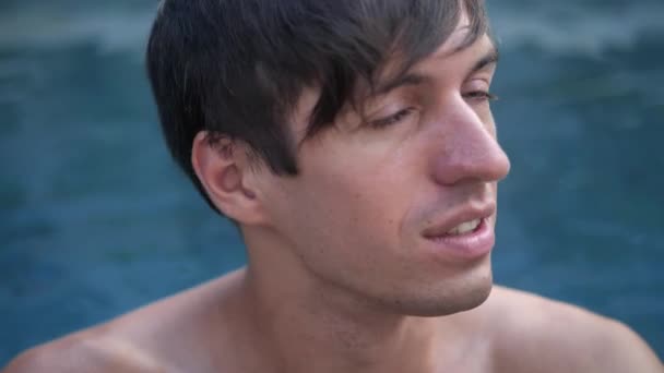 Крупним планом портрет молодого чоловіка розслабляється насолоджуючись в басейні — стокове відео