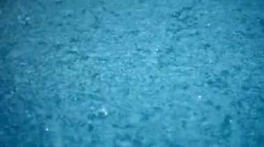 Close-up rainfall, raindrops falling to the surface of the water. Storm. Rain season.