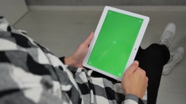 Sandalyede oturan ve yeşil ekran krom tuşlu dijital tablet kullanan adam