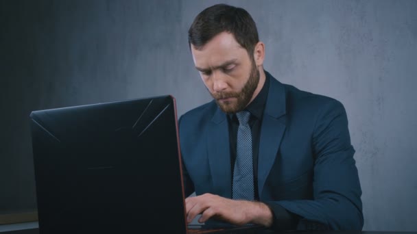 Homem de negócios bonito trabalhando com laptop enquanto sentado no escritório à noite — Vídeo de Stock