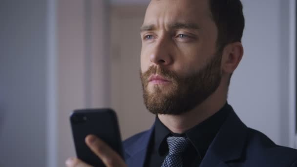 Portrait of confident businessman with a smartphone in his hands. The bearded boss solves the problem using a smartphone. — Stock Video