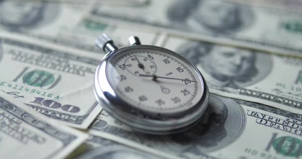 De stopwatch ligt op de dollars. Tijd is geld concept. — Stockvideo