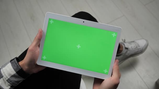 Чоловік сидить на стільці, дивлячись на цифровий планшет з зеленим екраном хром ключ — стокове відео