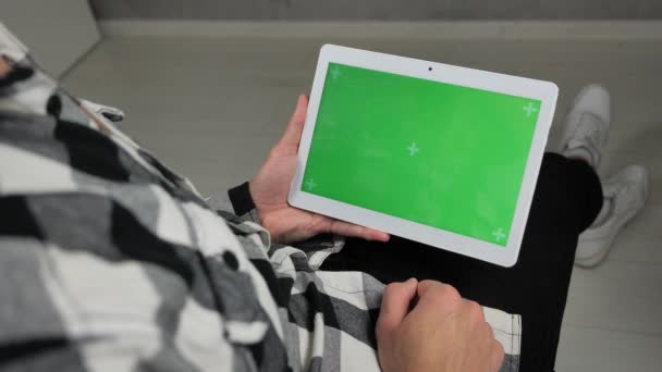 Mann sitzt auf Stuhl und nutzt digitales Tablet mit grünem Bildschirm — Stockvideo