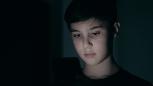 Портрет гарного хлопчика 10 років зі смартфоном вдома вночі . — стокове відео