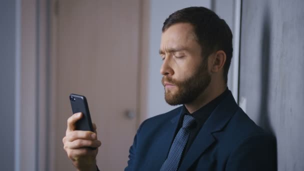 一个自信的商人手里拿着智能手机的画像。大胡子的老板用智能手机解决了这个问题. — 图库视频影像