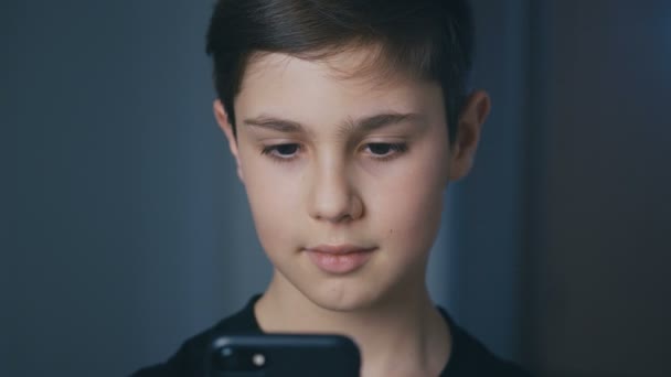 Niño jugando en su teléfono inteligente. Niño jugando juego móvil en el teléfono inteligente. Niño jugando videojuego en casa — Vídeos de Stock