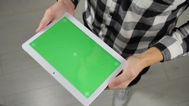 Adam ofiste duruyor ve elinde yeşil ekran krom anahtarıyla dijital tablet tutuyor.