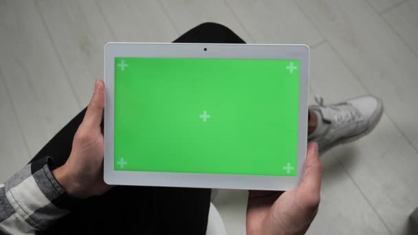 Man zittend op stoel kijkend naar digitale tablet met groene scherm chroma sleutel — Stockvideo