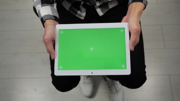 Mann sitzt auf Stuhl und schaut auf digitales Tablet mit grünem Bildschirm — Stockvideo