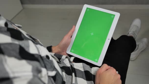 Uomo seduto sulla sedia guardando tablet digitale con chiave cromatica schermo verde — Video Stock