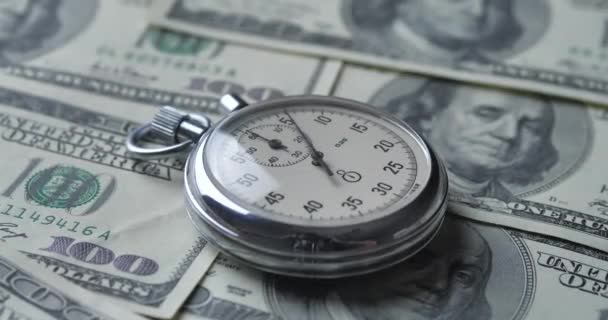 De stopwatch ligt op de dollars. Tijd is geld concept. — Stockvideo