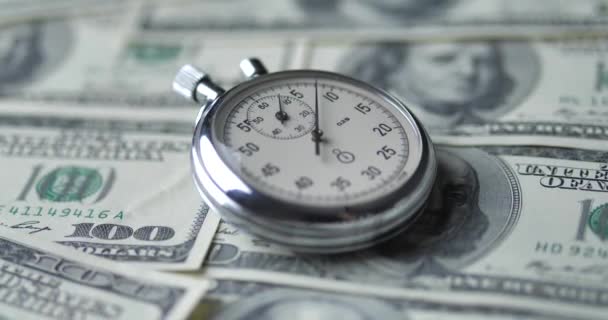 De stopwatch ligt op de dollars. Tijd is geld concept. — Stockvideo