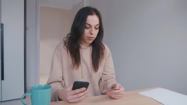 Jovem mulher compras online. Mulher sorridente on-line bancário usando smartphone compras on-line com cartão de crédito no estilo de vida em casa. Pagamento fácil usando gadget digital . — Vídeo de Stock